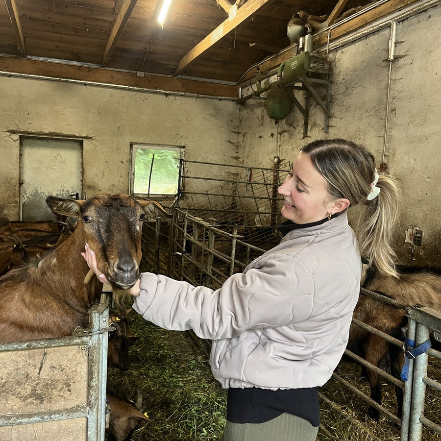 Tims Schwester streichelt eine Ziege im Stall