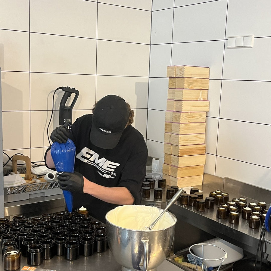Creme wird mit dem Spritzbeutel in Tiegel gefüllt